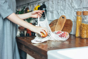 woman grabs fruit from reusable bag