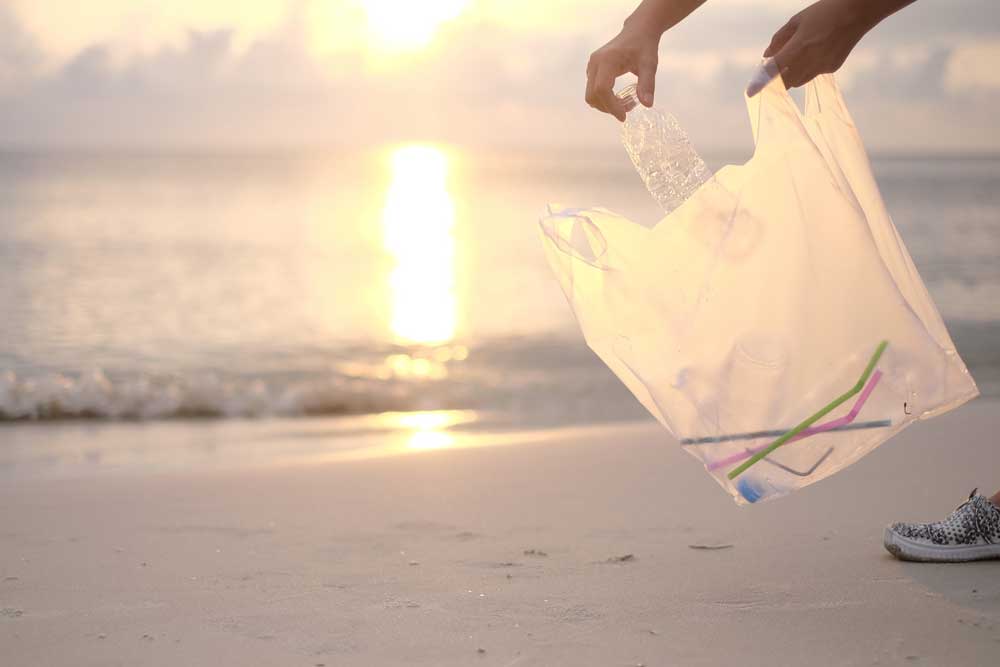 picking up trash on beach at sunset