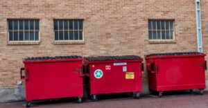 3 roll off dumpsters by industrial building