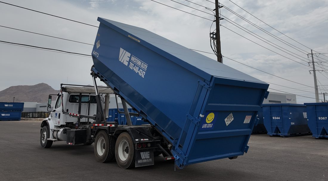 Western Elite roll-off truck setting a placarded blue asbestos container